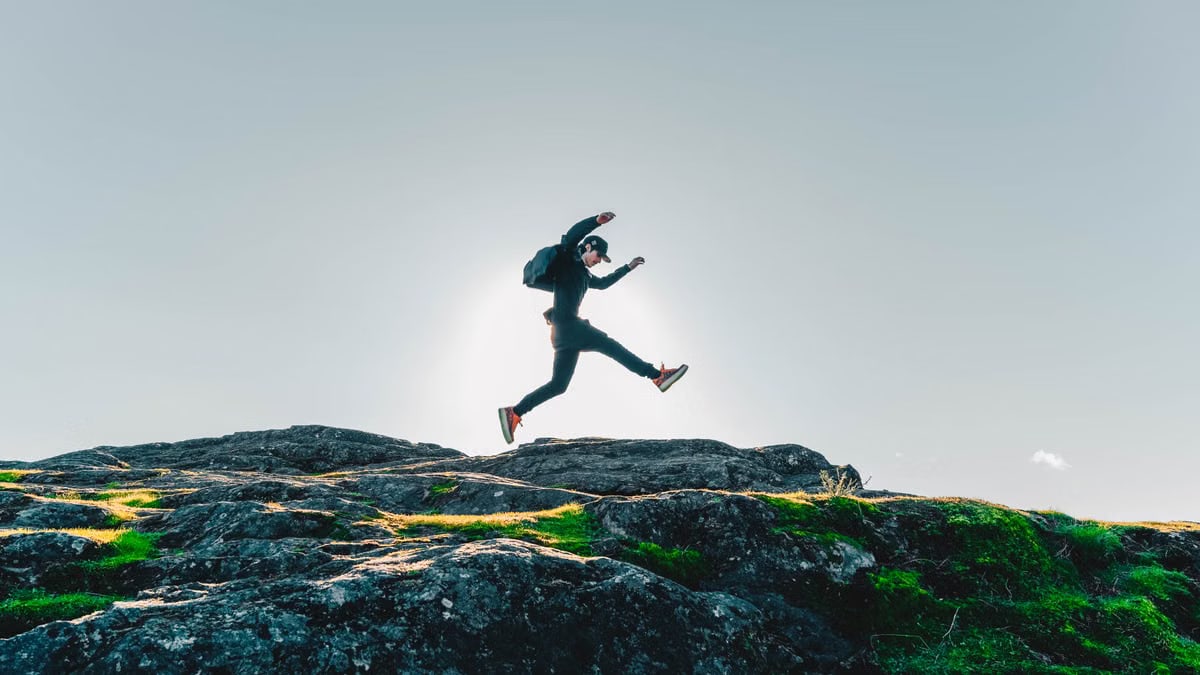 A person jumping over rocks with a clear sky background in British Columbia, Canada.